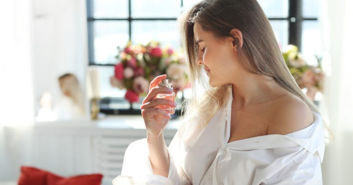 A woman in a white shirt holding a perfume bottle, ready to add a touch of elegance to her day.