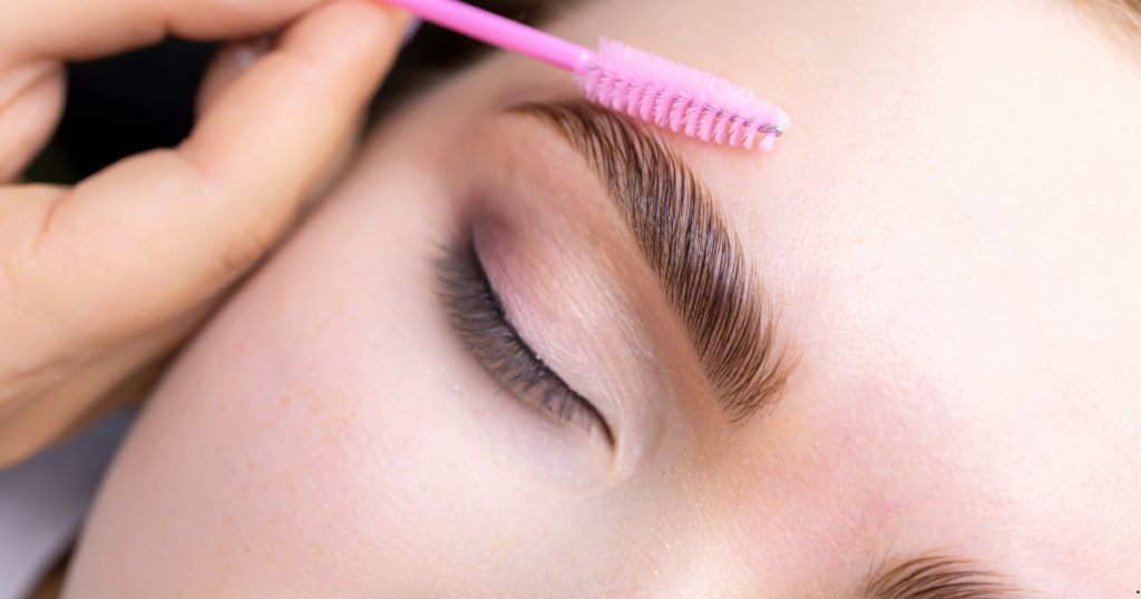 A woman getting her eyebrows done with a pink brush