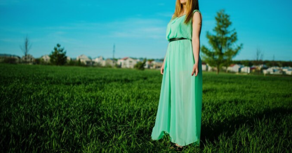 A woman in a long green dress standing in a field